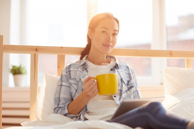 Mulher asiática, bebendo café, cama