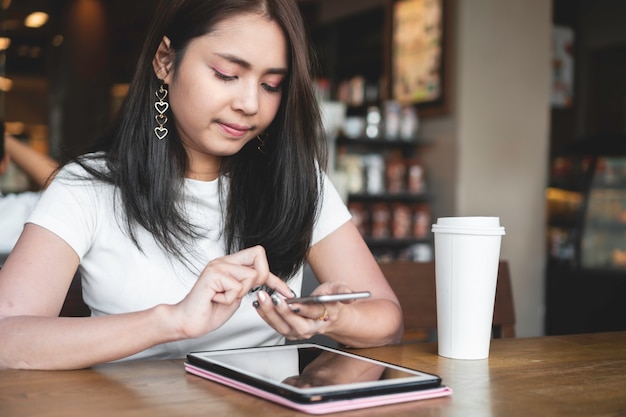 Mulher asiática bem sucedida usando smartphone para negócios on-line no café café.