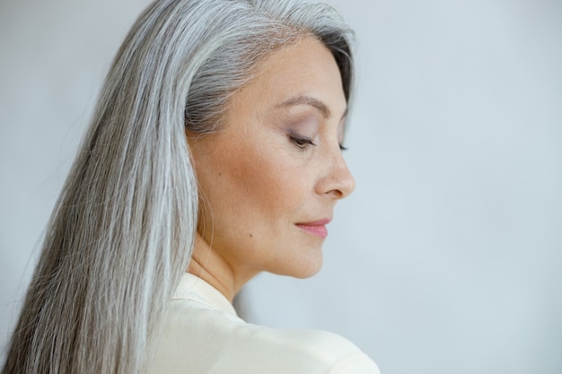 Foto mulher asiática bonita de meia-idade com cabelo grisalho liso solto em fundo claro