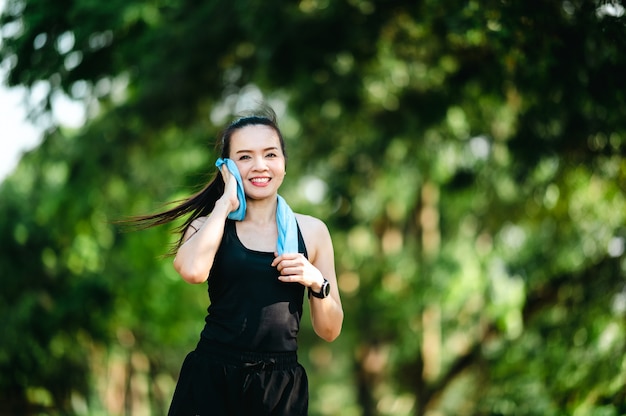 Mulher asiática bonita do esporte de meia-idade caminhando ao ar livre no parque sorrindo vivendo um estilo de vida ativo e saudável.