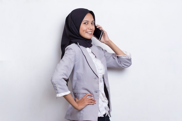 Mulher asiática bonita muçulmana jovem feliz usando telefone celular isolado no fundo branco