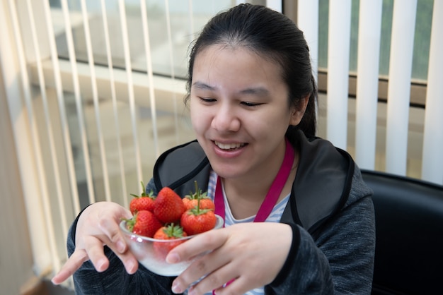 Mulher asiática bonita segurando e comendo morango fresco