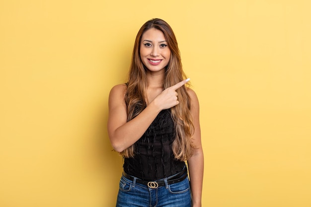 Mulher asiática bonita sorrindo alegremente, feliz e apontando para o lado