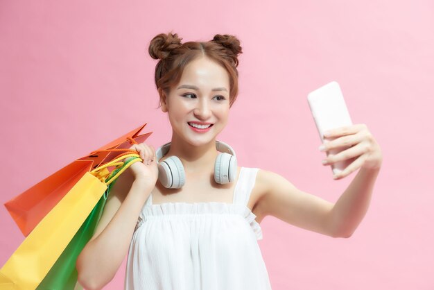 Mulher asiática carregando uma sacola de compras e olhando para o telefone