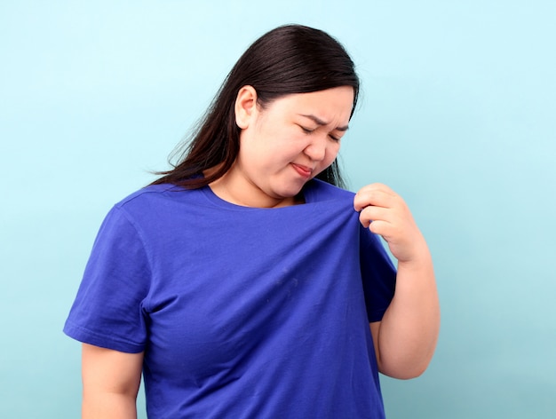 Mulher asiática cheira mal com camisa suja.