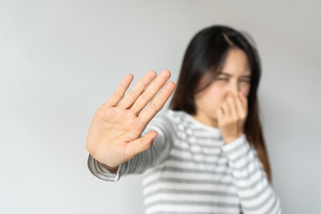 Mulher asiática cheirando algo fedido e repugnante cheiro intolerável prendendo a respiração com os dedos no nariz Garota aperta o nariz com os dedos parece com nojo algo cheira mal cheiro Copiar espaço