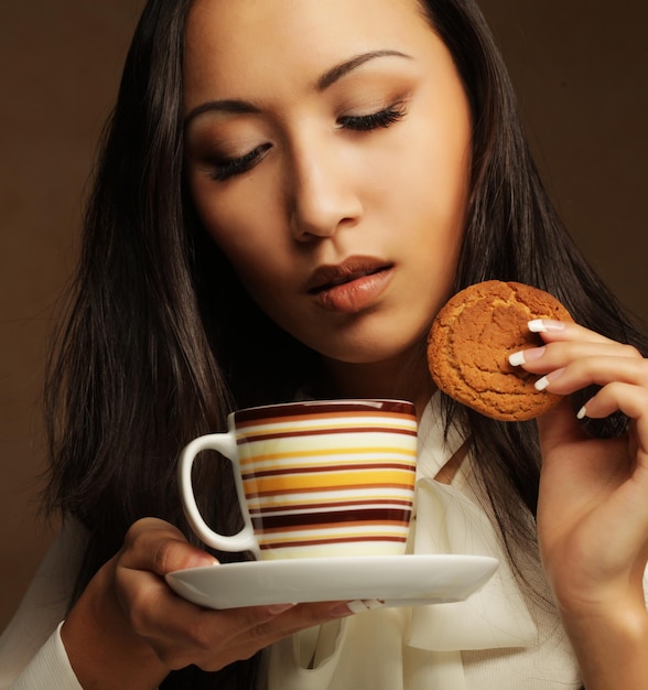 Mulher asiática com café e biscoitos.