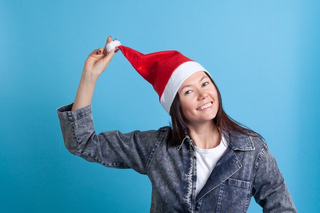 Mulher asiática com chapéu de papai noel levanta o chapéu