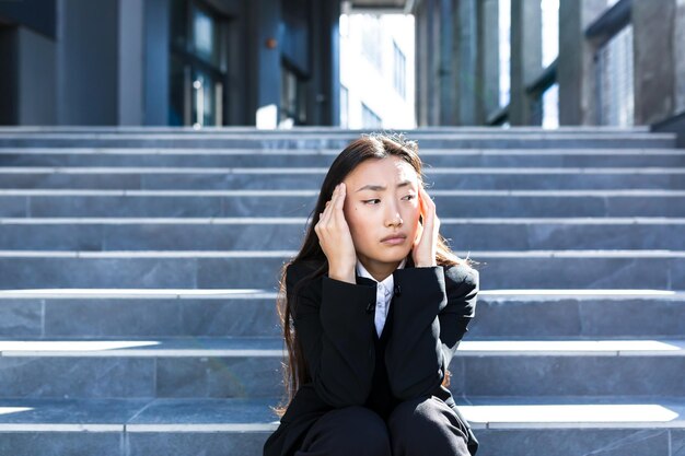 Mulher asiática com cocar forte sentado nas escadas, empresária deprimida doente e triste