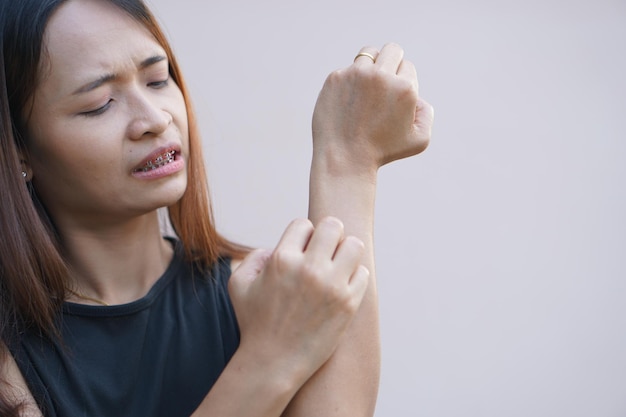 Mulher asiática com coceira na pele do braço