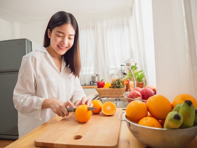 Mulher asiática com frutas na cozinha