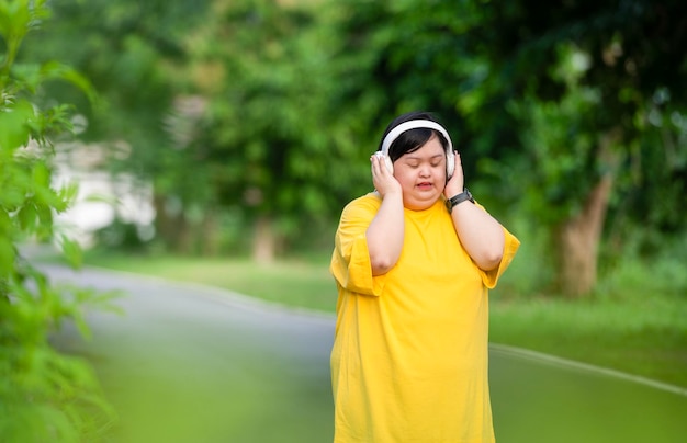 Mulher asiática com síndrome de Down vestindo roupas casuais e ouvindo música Sorrisos felizes no parque durante o exercício Pessoa positiva