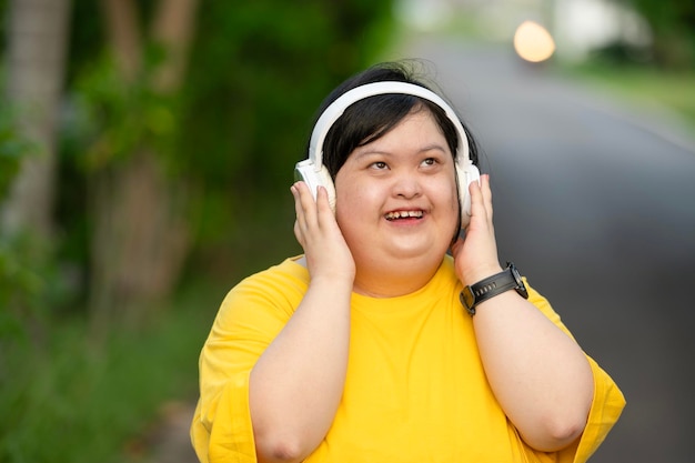 Mulher asiática com síndrome de Down vestindo roupas casuais e ouvindo música Sorrisos felizes no parque durante o exercício Pessoa positiva