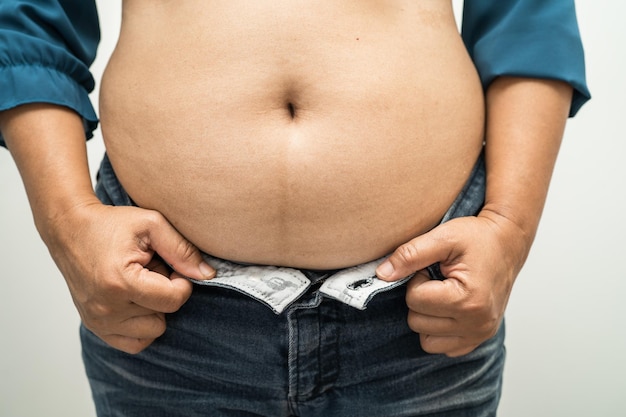 Mulher asiática com sobrepeso mostra barriga gorda no escritório