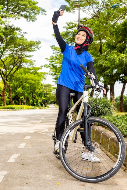 Mulher asiática com um capacete usando um telefone celular em sua bicicleta