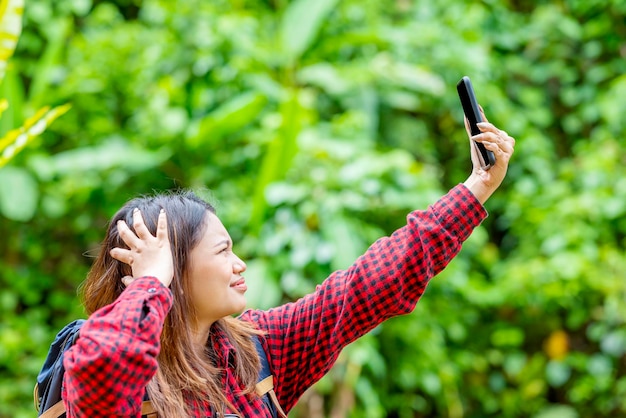 Mulher asiática com uma mochila procurando o sinal para seu celular