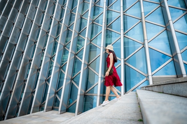 Mulher asiática com vestido vermelho em edifício moderno, menina com estilo de vida urbano