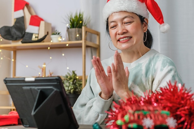 Mulher asiática comemora ano novo e festa de Natal com amigos de videochamada em tablets em casa