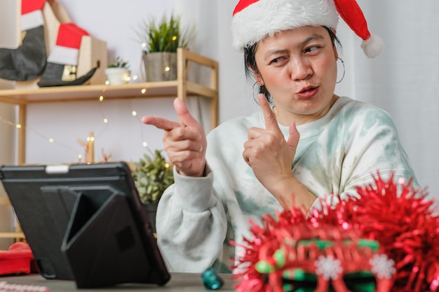 Mulher asiática comemora ano novo e festa de Natal com amigos de videochamada em tablets em casa