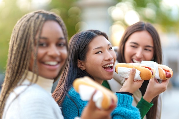 Foto mulher asiática comendo cachorro-quente com amigos em um parque