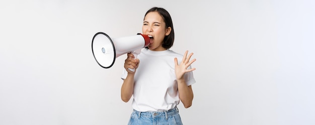 Mulher asiática confiante gritando no megafone gritando e protestando ativista feminina usando alto-falante para