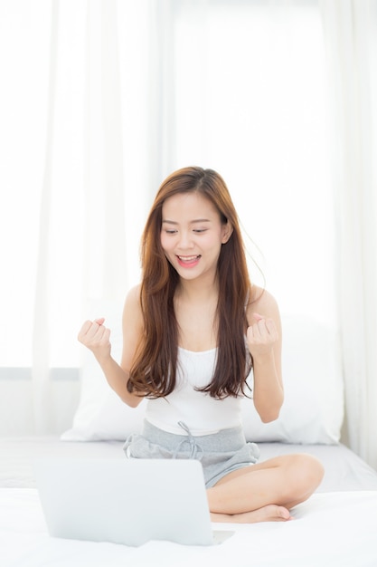 Mulher asiática da felicidade bonita que usa o trabalho do portátil com sucesso.