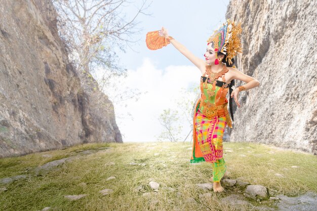 Mulher asiática dançando dança tradicional balinesa (dança kembang girang) ao ar livre