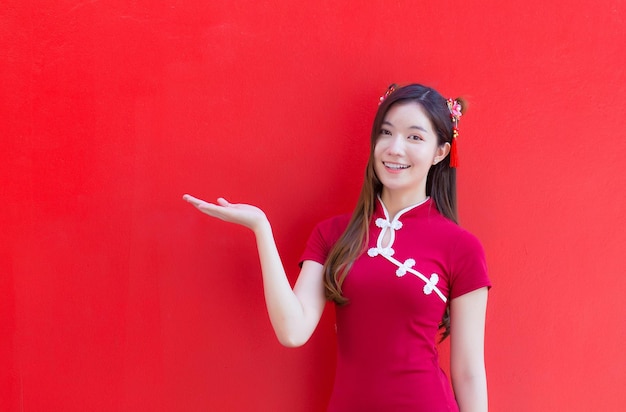 Mulher asiática de cabelo comprido usa vestido chinês vermelho ou fundo vermelho qipao com tema de ano novo chinês