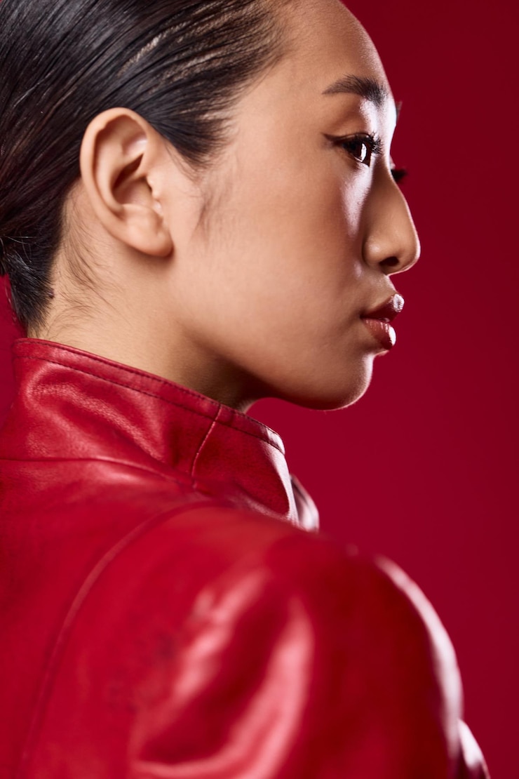 Foto mulher asiática de moda com jaqueta de couro vermelha posando em um fundo vermelho