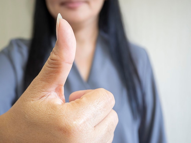 Mulher asiática de sucesso apontando o polegar para cima gesto de sinal