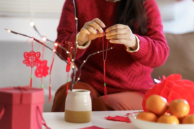 Mulher asiática decora casa para celebrações do Ano Novo Chinês colocando pingente tradicional para o Ano Novo Lunar Chinês para boa sorte palavra chinesa significa bênção