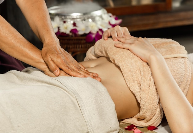 Mulher asiática desfrutando de uma massagem de esfoliação com sal no spa Spa de saúde e conceito tailandês de massagem Garota recebendo tratamento de massagem holística mulher massagista tailandesa recebendo massagem