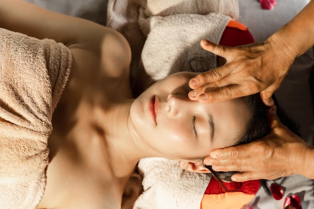 Mulher asiática desfrutando de uma massagem de esfoliação com sal no spa Spa de saúde e conceito tailandês de massagem Garota recebendo tratamento de massagem holística mulher massagista tailandesa recebendo massagem