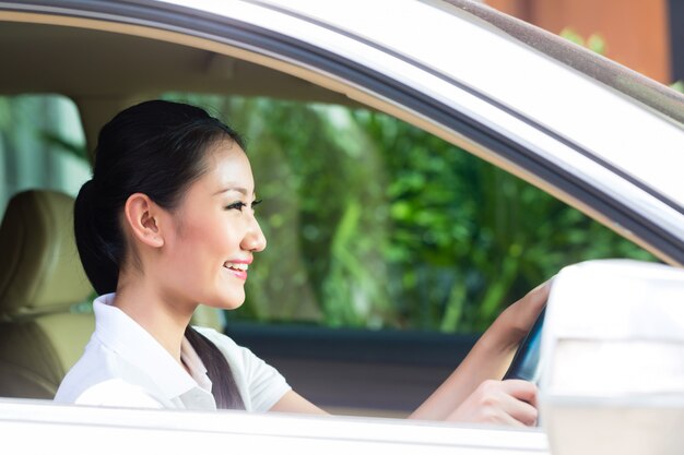 Mulher asiática dirigindo carro novo