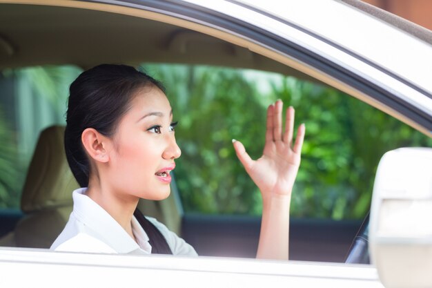 Mulher asiática dirigindo carro novo