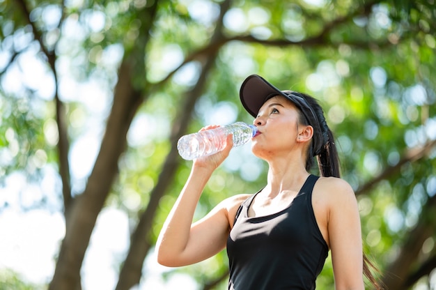 Mulher asiática do esporte bonito de meia-idade bebendo água após o conceito de corrida, saúde e esporte.