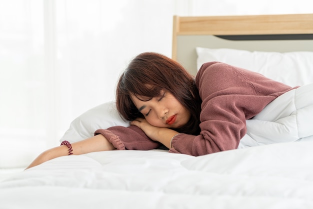 Mulher asiática dormindo na cama pela manhã