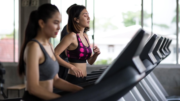 Foto mulher asiática e amigos fazendo exercícios em esteiras em um ginásio de fitness esportivo com espaço de cópia para texto