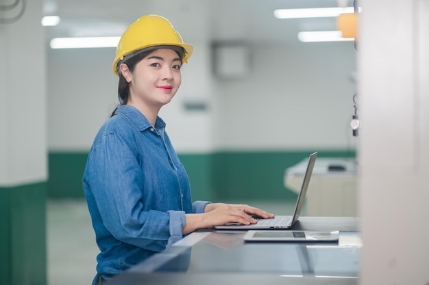 Mulher asiática é engenheira de fábrica inspecionando máquina na fábrica com computador Engenheira asiática trabalhando no conceito de fábrica