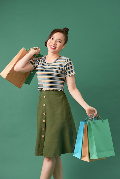 Mulher asiática elegante sorrindo e segurando sacolas de compras