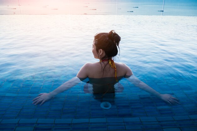 Mulher asiática em biquíni relaxante na piscina verão comcept