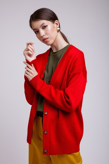 Mulher asiática em calças amarelas cardigan vermelho cinto de camiseta verde sobre fundo branco Fotografia de Estúdio