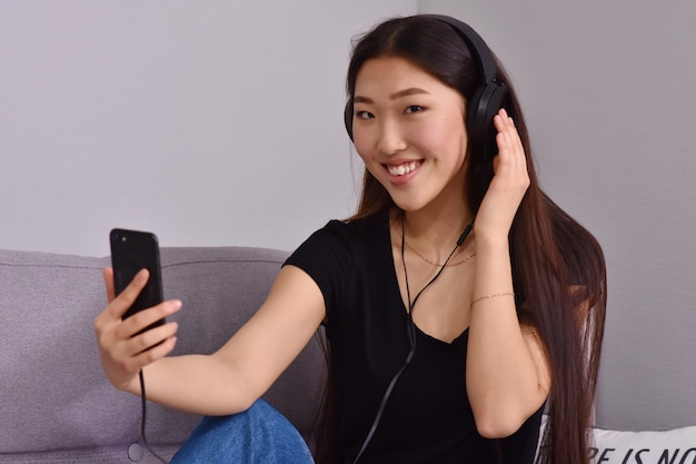 Mulher asiática em fones de ouvido usando smartphone