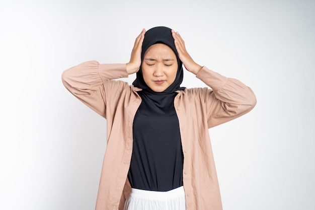 Mulher asiática em hijab segurando a cabeça com dor de cabeça