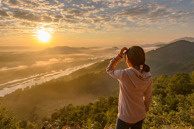 Foto mulher asiática em pé, assistindo o nascer do sol e o mar de névoa no rio mekong, tailândia