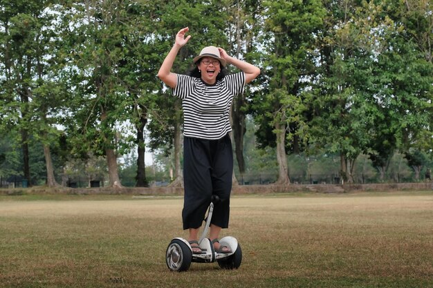 Mulher asiática em roupas casuais montando uma prancha no parque