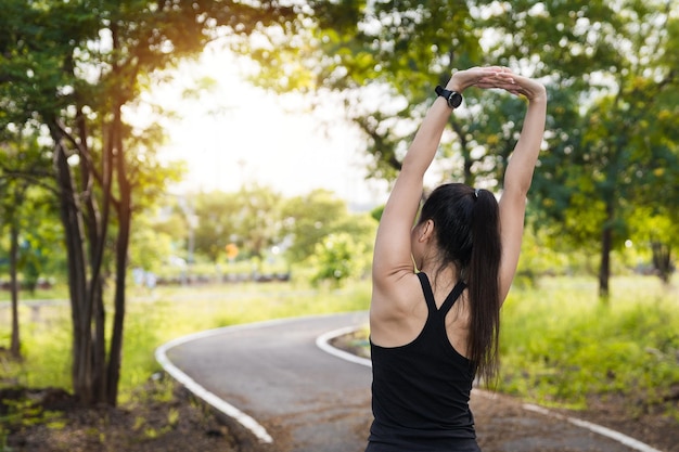 Mulher asiática em roupas esportivas fazendo alongamento antes do treino ao ar livre no parque pela manhã