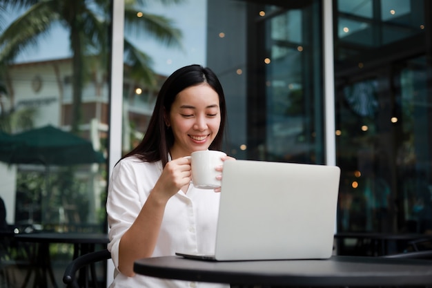 Foto mulher asiática em um café trabalhando em um laptop