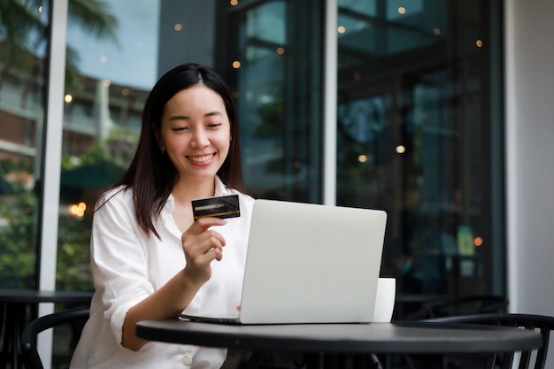 Foto mulher asiática em um café trabalhando em um laptop