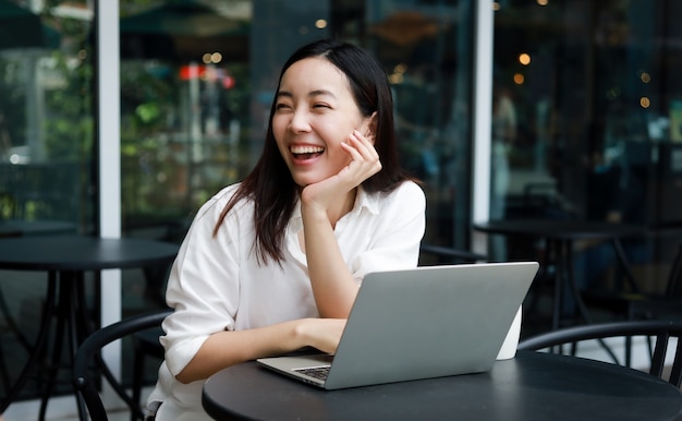 Foto mulher asiática em um café trabalhando em um laptop